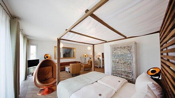A modern hotel room with a canopy bed, a hanging chair, a desk, and a stone wall. - Appartement in Strausberg mit Frühstück inklusive (Strausberg)