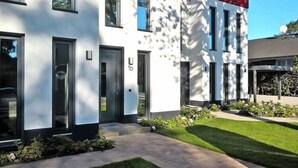 A modern building with a white facade, numbered doors, and a well-maintained lawn. - Appartement in Strausberg mit Frühstück inklusive (Strausberg)