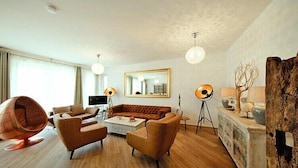 A modern living room with a sofa, armchairs, a coffee table, a hanging chair, and a large mirror. - Appartement in Strausberg (Strausberg)