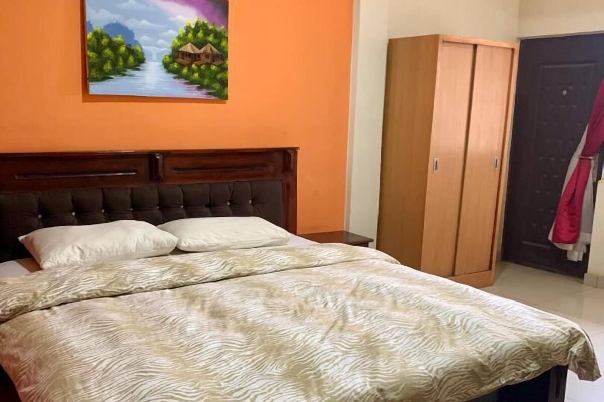 Quarto com cama, quadro, guarda-roupa e tapete vermelho.