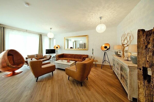 A modern living room with a sofa, armchairs, a coffee table, and a unique egg-shaped chair.