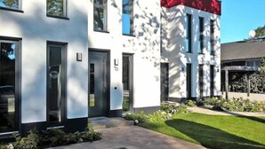 A modern building with a white facade, numbered doors, and a well-maintained lawn. - Appartement in Strausberg mit Frühstück inklusive (Strausberg)