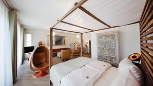 A modern hotel room with a large bed, a hanging chair, a desk, and a stone wall. - Appartement in Strausberg mit Frühstück inklusive (Strausberg)