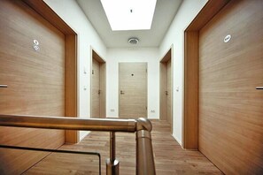 A hallway with wooden doors, a skylight, and a metal handrail.