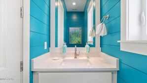 Un baño con un lavabo blanco, paredes azules y un espejo grande.