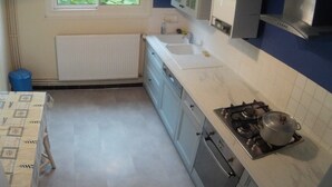Una cocina con ventana, armarios blancos, un fregadero y una estufa.