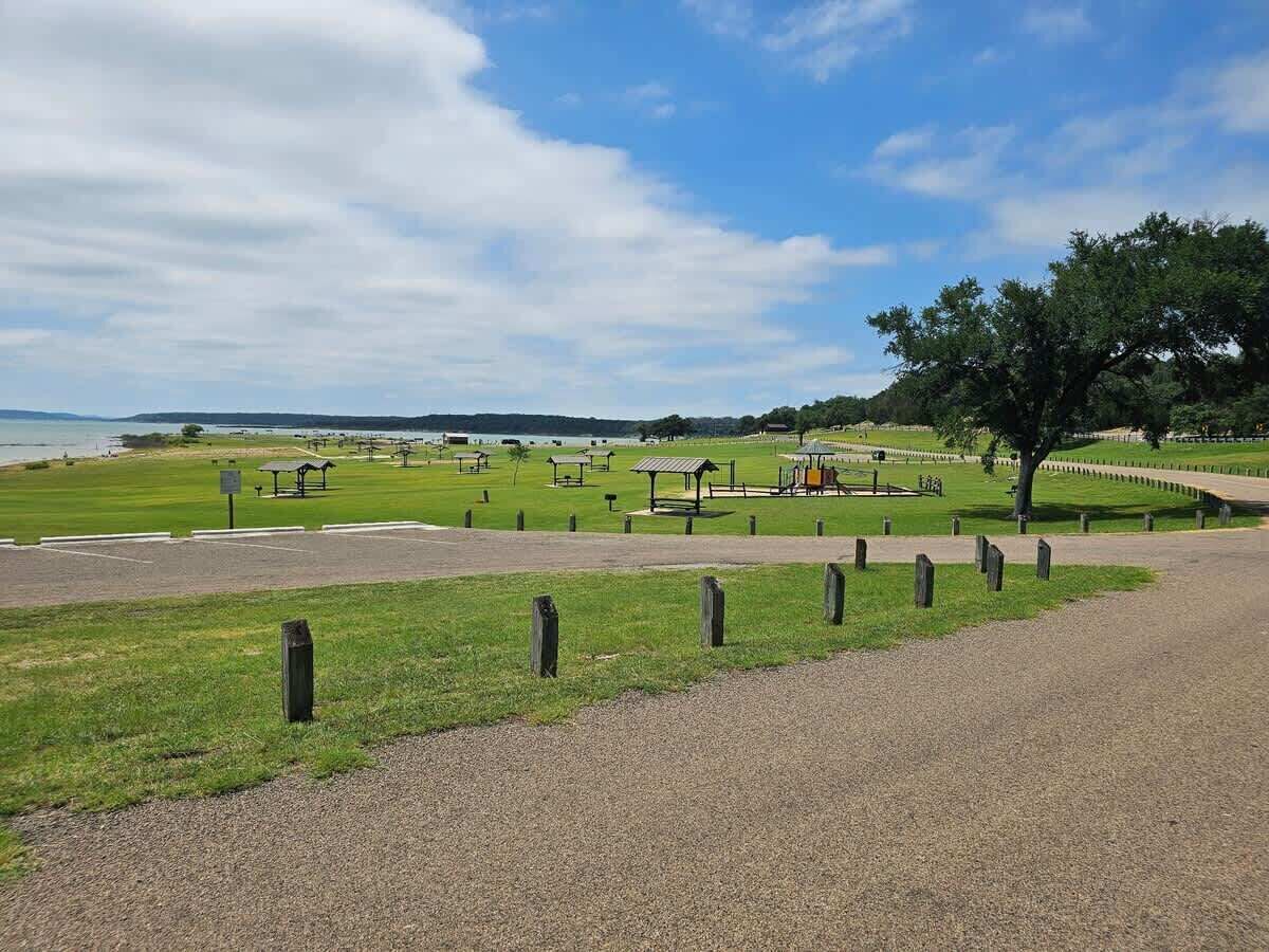 A cemetery with headstones, a large tree, and a body of water in the background.