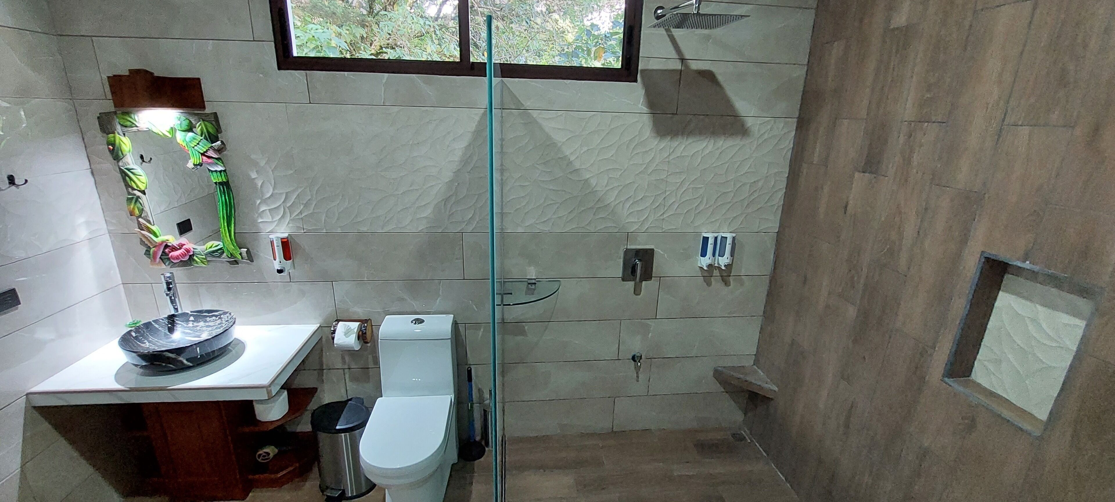 A modern bathroom with a marble sink, toilet, and glass shower enclosure.