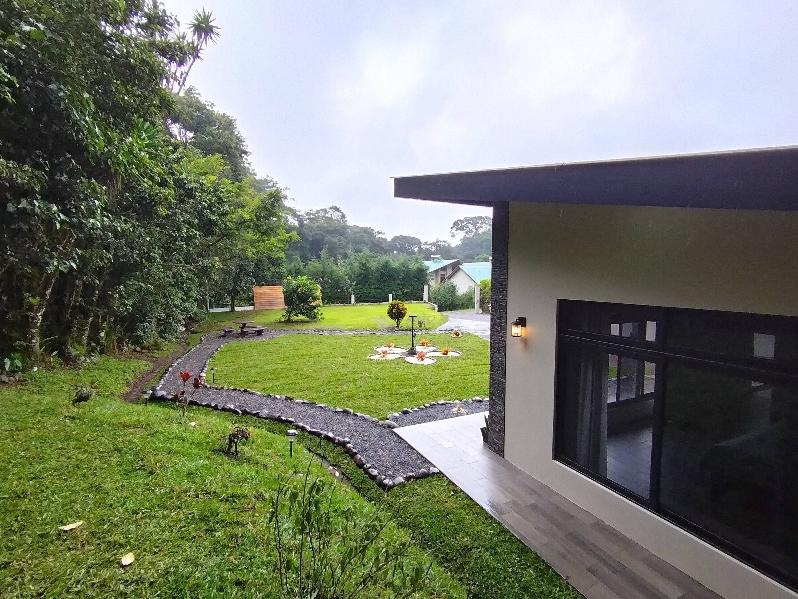 A modern building with a large window, a well-maintained lawn, and a stone pathway.