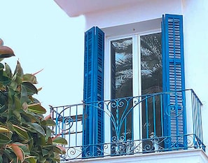 A balcony with blue shutters and ornate metal railings.