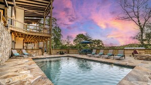 A pool area with stone flooring, lounge chairs, and a wooden deck with a view of the sky. - EPIC Pool * View * Outdoor Kitchen * Luxury (Mineral Bluff)