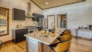 A kitchen with a central island, dark cabinets, a stainless steel range hood, and a wooden ceiling. - EPIC Pool * View * Outdoor Kitchen * Luxury (Mineral Bluff)