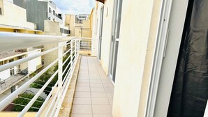 A narrow balcony with white railings, a tiled floor, and a view of neighboring buildings. - FUN GAME St. Julians Apartment 3 (San Ġiljan)