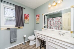 A bathroom with a toilet, sink, and mirror.
