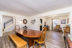 A spacious dining area with a wooden table and chairs, a bench, and a staircase leading to another room.