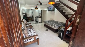 A modern living room with a sofa, a bed, a staircase, and a TV mounted on the wall. - Modern House in Dunas Beach (cabo frio)