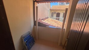 A narrow corridor with a view of a tiled roof and a building with a balcony. - Modern House in Dunas Beach (cabo frio)