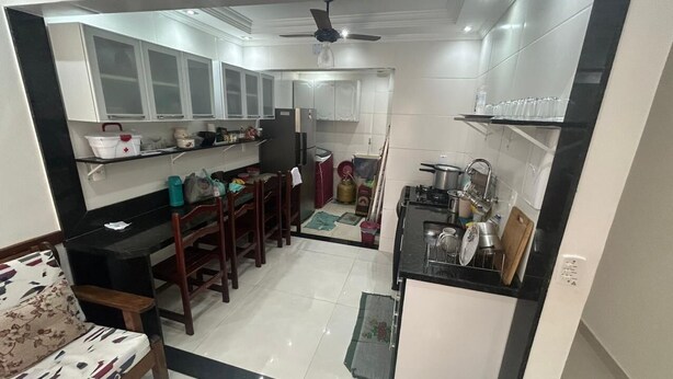 A compact kitchen with white cabinets, a dining area with a wooden table and chairs, and a ceiling fan. - Modern House in Dunas Beach (cabo frio)
