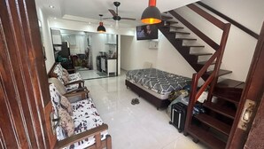A modern living room with a sofa, a bed, a TV, and a staircase. - Modern House in Dunas Beach (cabo frio)