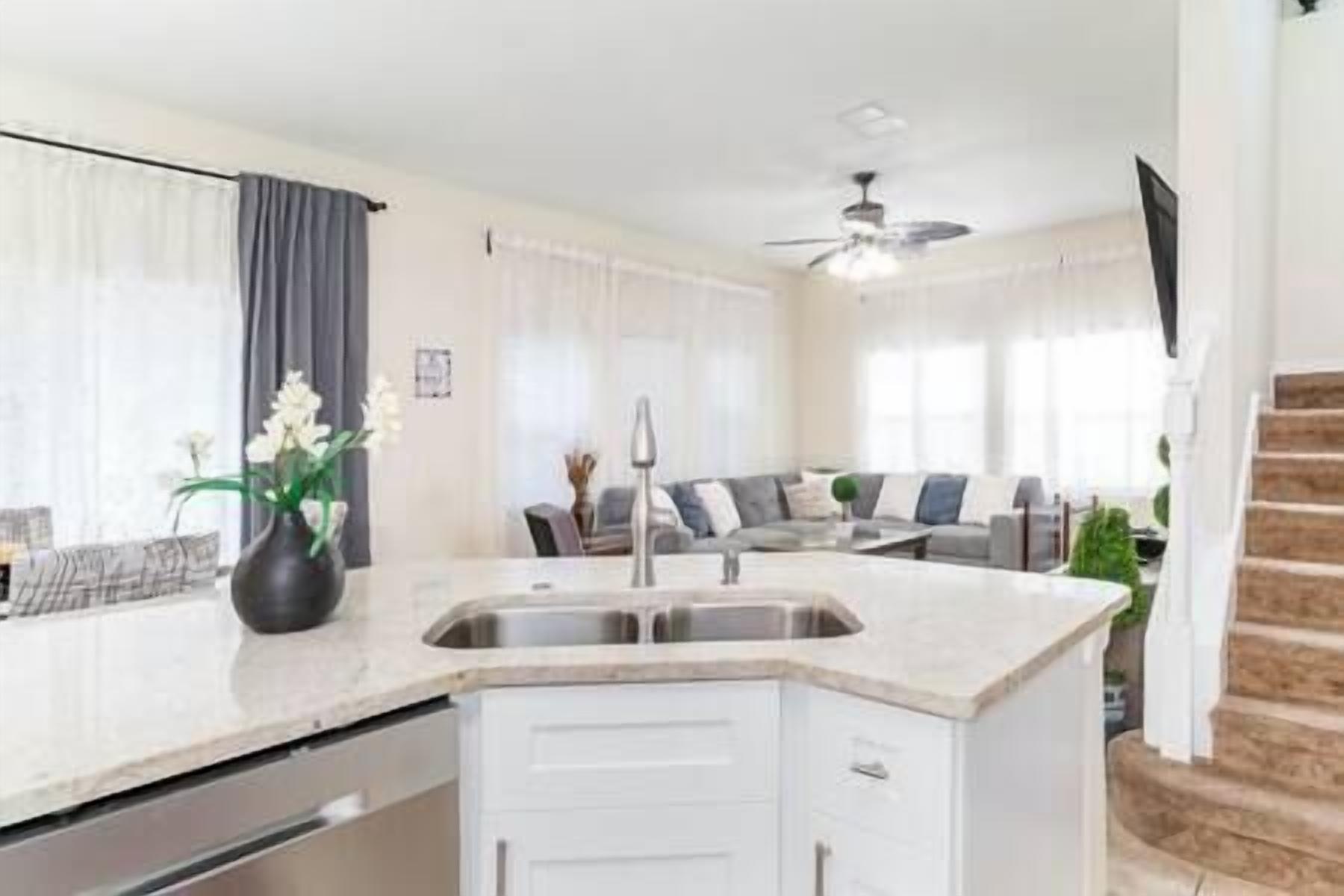 A modern kitchen with a built-in island, a dining area with a sofa, and a staircase.
