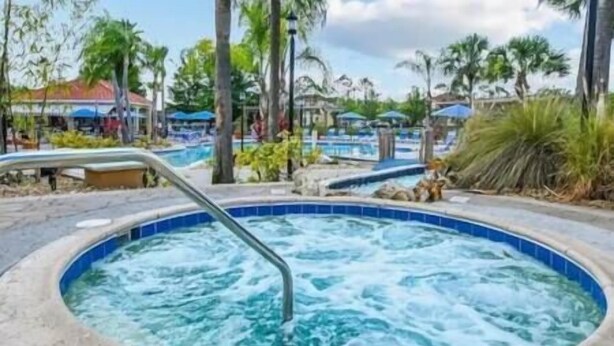 Ein Bereich mit Whirlpool und Pool, umgeben von Palmen und Sonnenschirmen.