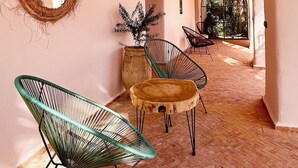 Un couloir orné de lanternes suspendues, d’un miroir décoré de motifs tissés et de chaises modernes.