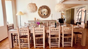 Un coin repas avec une table et des chaises en bois, un miroir et un lustre.
