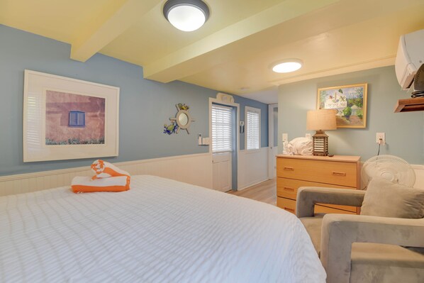 Ein Schlafzimmer mit einem großen Bett, einem Schminktisch, einem Sessel und einem Bild an der Wand.