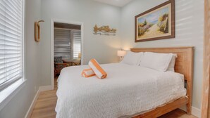 Un dormitorio con una cama, un cuadro, una lámpara y un ventilador de techo.