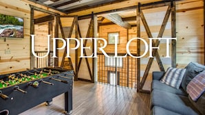 A cozy room with a foosball table, a sofa, and wooden beams on the ceiling.