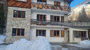 A multi-story building with stone walls and wooden balconies, surrounded by snow. - 2-bedroom apartment LA GIETTAZ 4 km from the ski slopes with free shuttle service (La Giettaz)