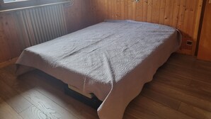 A small room with a single bed, wooden walls, a window with a view of a vehicle, and a radiator. - 2-bedroom apartment LA GIETTAZ 4 km from the ski slopes with free shuttle service (La Giettaz)