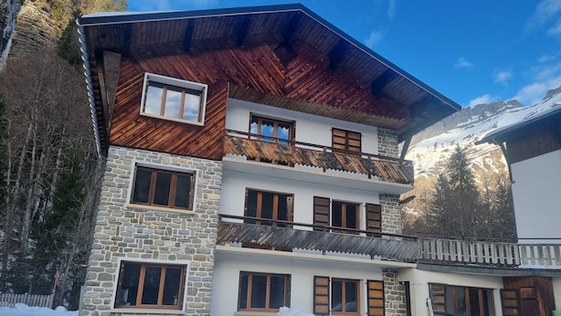A multi-story building with stone and wooden exterior walls, multiple windows, and a balcony. - 2-bedroom apartment LA GIETTAZ 4 km from the ski slopes with free shuttle service (La Giettaz)