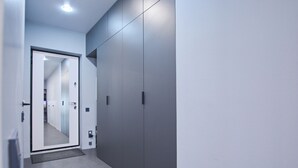 A hallway with a mirrored door, grey walls, and a grey floor. - Aparton.by - Makaenka 12G-1x6 str. (Minsk)