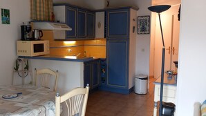 Une cuisine de taille réduite avec des meubles bleus, un four à micro-ondes et un évier.