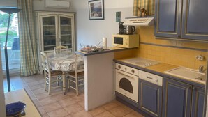 Une cuisine compacte avec un coin repas, comprenant un four à micro-ondes, un four et un petit évier.