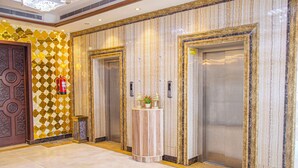 A lobby with two elevators, a decorative wall, and a small table with a vase.