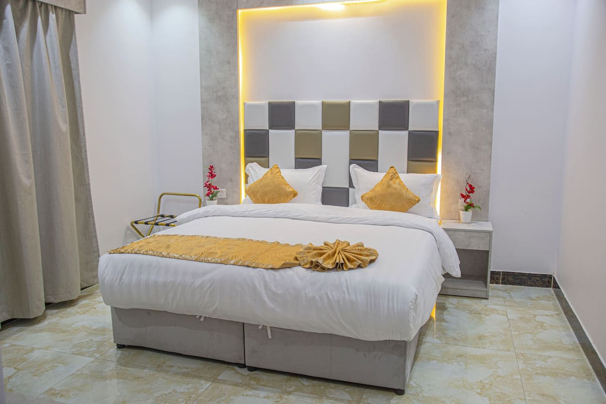 Een moderne hotelkamer met een groot bed, een nachtkastje en een klein tafeltje.