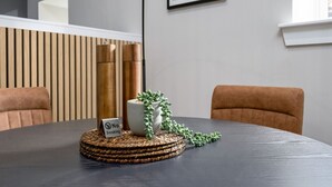 Een ronde tafel met een geweven onderzetter, een witte mok en twee hoge, cilindervormige objecten.