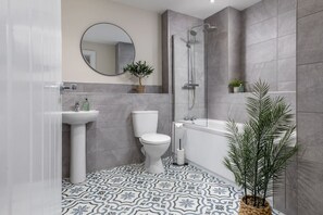 Une salle de bain moderne équipée de toilettes, d’un lavabo, d’une douche et d’une baignoire.