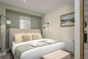 Une chambre à coucher moderne avec un grand lit, des lampes de chevet, un radiateur et un tableau au mur.
