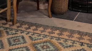 En hyggelig krog med en flettet stol, en lampe, et indrammet maleri og en pejs.