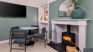 Ein modernes Wohnzimmer mit Kamin, einem runden Tisch und grau gepolsterten Sesseln.