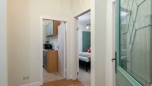 Ein schmaler Flur mit einer Küchenzeile links und einem Schlafzimmer rechts.