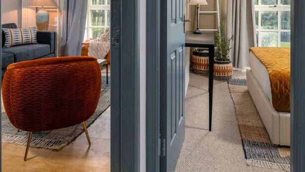 Une chambre d’hôtel moderne avec une grande fenêtre, un canapé, un fauteuil et un lit.