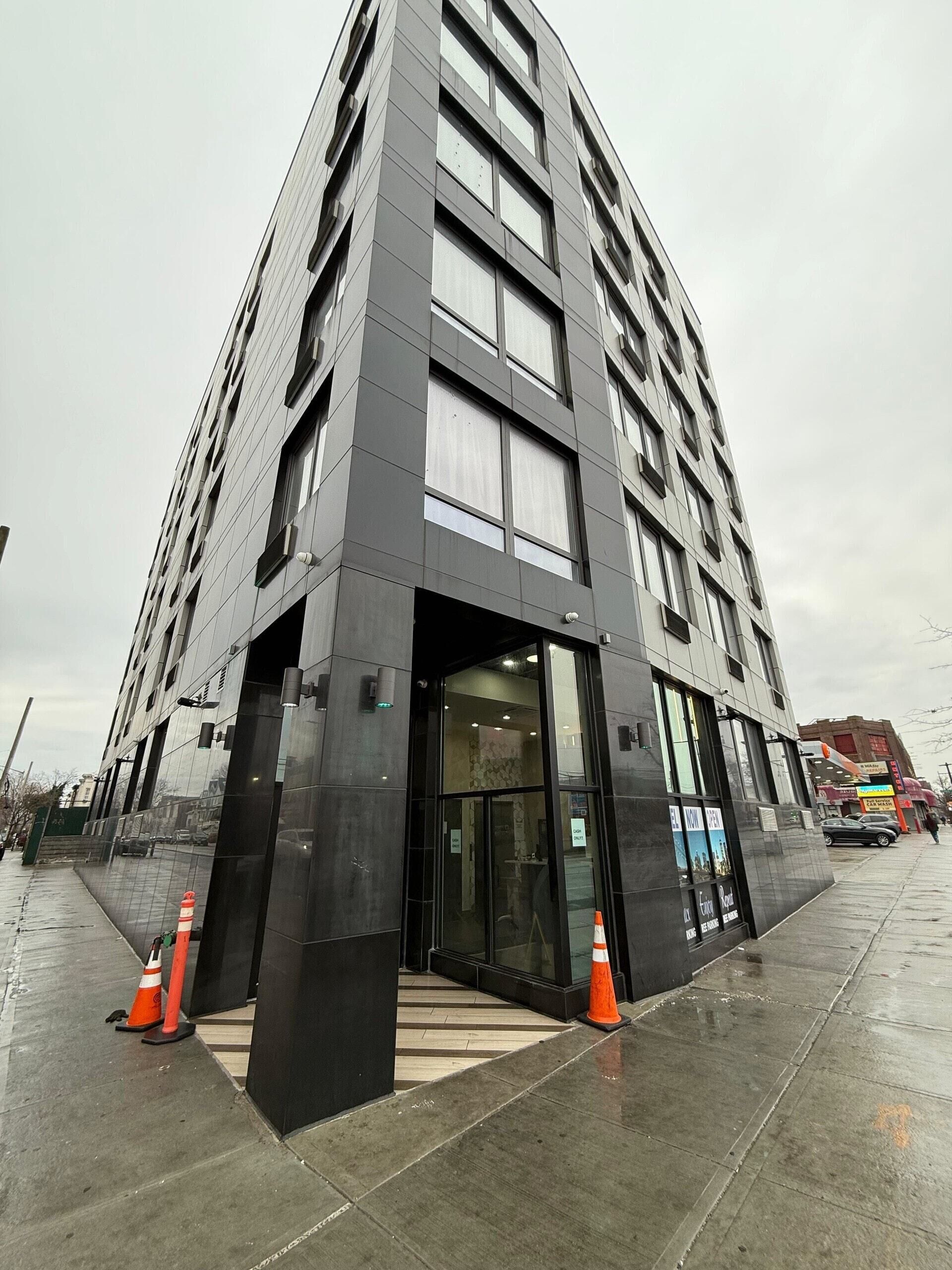 A modern building with a glass entrance and black exterior.