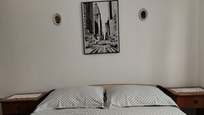 Una cama bien hecha con ropa de cama de lunares y dos toallas enrolladas.