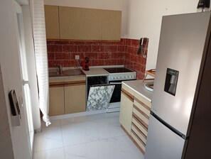 Eine kleine Küche mit Herd, Spüle und Kühlschrank.