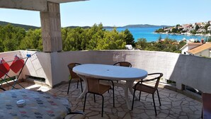 Un balcón con mesa y sillas, con vista a un pueblo costero y al mar.