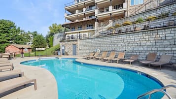 A swimming pool with lounge chairs and a stone wall.